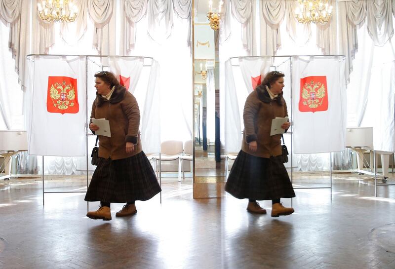 A woman is reflected in a mirror while leaving a voting booth at a polling station during the presidential election in Moscow, Russia March 18, 2018. REUTERS/David Mdzinarishvili
