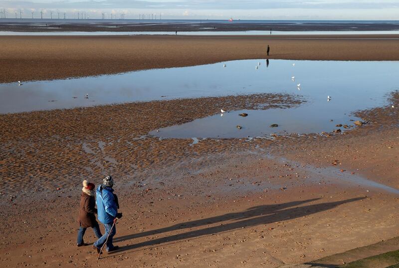 A couple walk along a quiet beach in Crosby. Reuters
