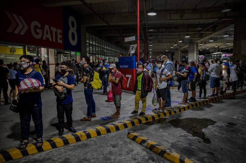 Commuters queue at a bus station in Parañaque, Metro Manila. Getty Images