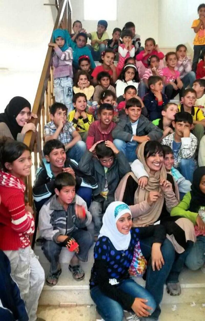 Muna Harib sitting among Syrian refugee children in May. Ms Harib will be leading a team of 14 people, including five Emiratis, to hand out aid to Syrian refugees. Courtesy Muna Harib