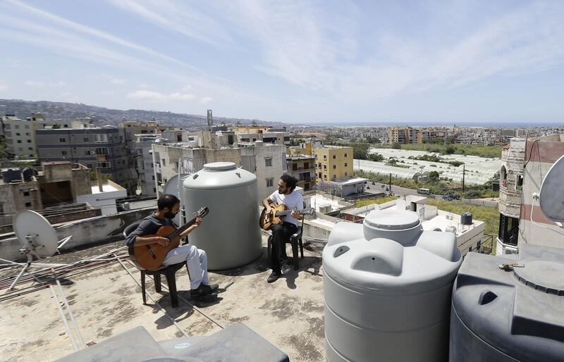 Lebanese Musician Ziad al-Zayyat (L) and his flatmate, interior designer Saad Molaeb, play their guitars on the rooftop of their building, during a lockdown imposed by the authorities in the town of Hadath, north of the capital Beirut on May 4. Usually the kingdom of water tanks and satellite dishes, Lebanon's roofs have recently been graced by unlikely scenes of confined residents fleeing their flats for space and fresh air. Joseph Eid/ AFP