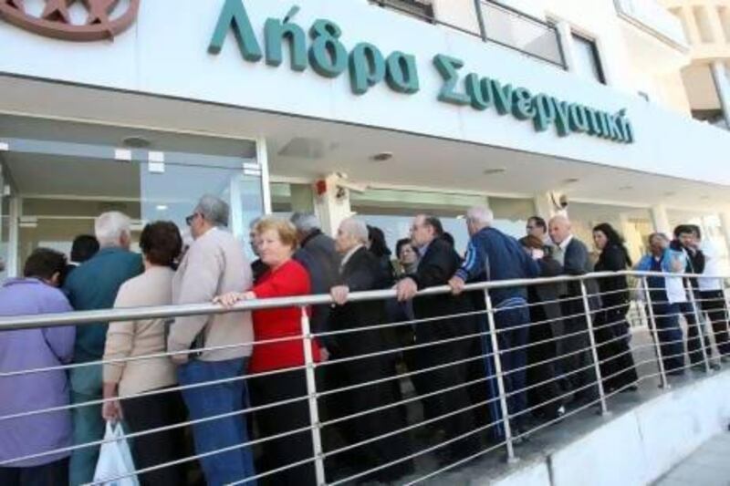 People wait in a long queue outside a branch of the COOP Bank in Nicosia, Cyprus.  All of the country's 26 banks were open from 12pm until 6pm yesterday.