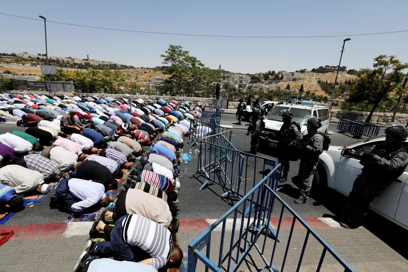 Israeli policemen stand guard as Palestinian men take part in Friday prayers outside Jerusalem's Old City July 14, 2017. REUTERS/Ammar Awad