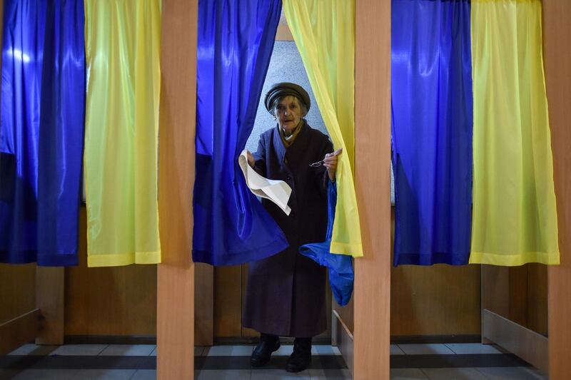 An elderly woman walks out of a voting booth at a polling station during Ukraine's presidential election in Kiev. AFP