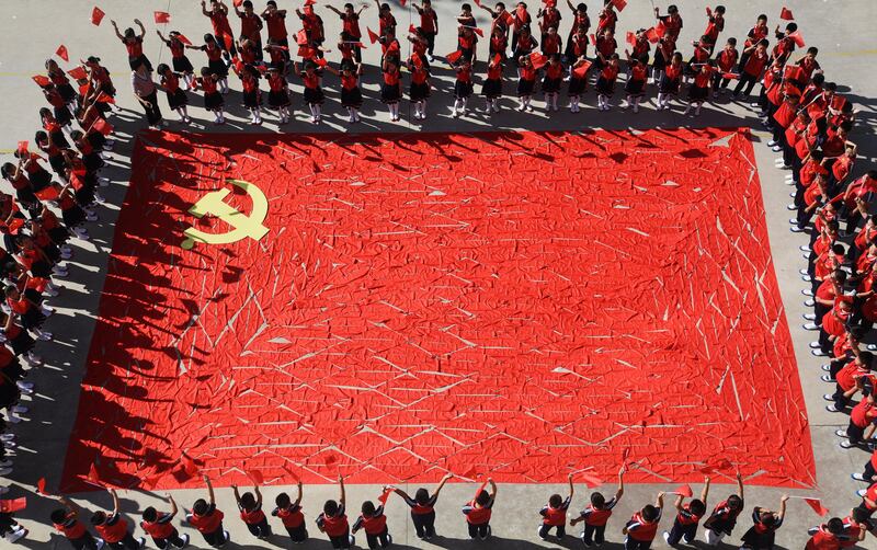 Students from the Linyi primary school in Shandong province stand around a flag of the Communist Party of China made of red scarves, ahead of the party's 19th national congress. Reuters