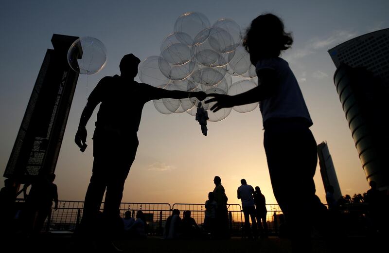 A balloon vendor sells light balloons while people watch fireworks over the sky of Dubai Festival City (DFC) on the second day of Eid Al-Fitr in UAE. EPA