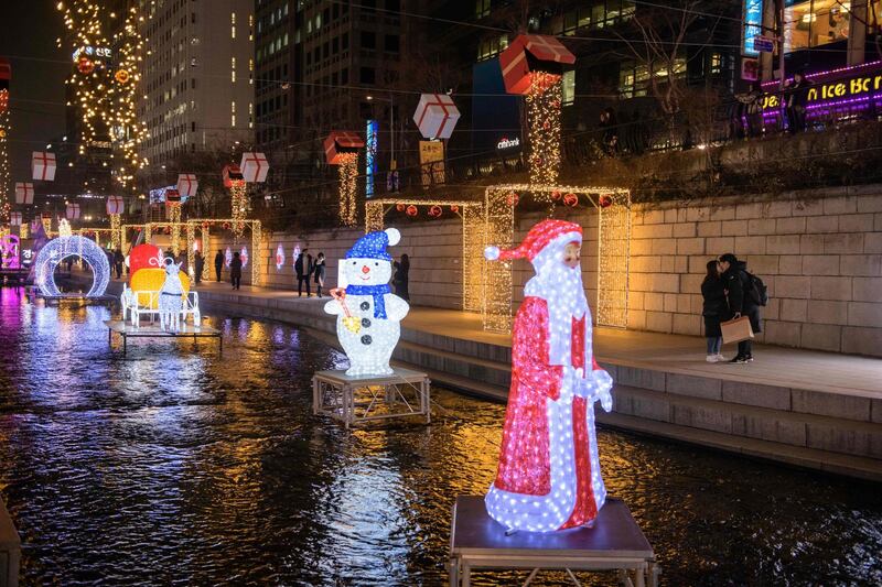 A couple kiss behind a Christmas-themed light display at along the Chongye stream in central Seoul.  AFP