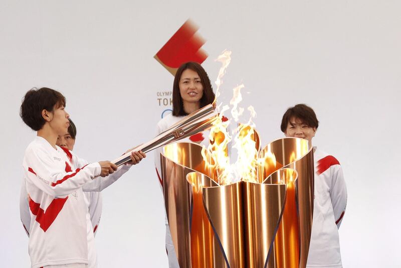 Torchbearer Azusa Iwashimizu, a member of Japan national football team, lights the Olympic torch on day one of the relay in Naraha, Fukushima. AFP