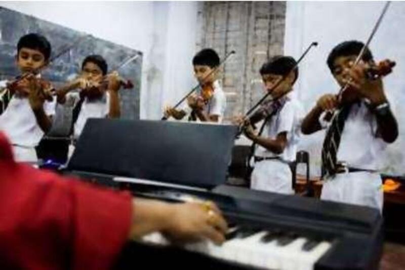 Students practice violin as the music teacher, Abraham Majumdar helps with a background piece on the piano in a music class at the La Martiniere School for Boys in Calcutta, India *** Local Caption ***  sdas070708_calcutta_0170.jpg