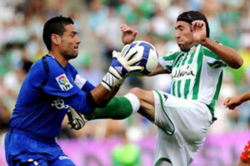 Sevilla's keeper Andres Palop grabs the ball off the toes of the Betis striker Mariano Pavone.