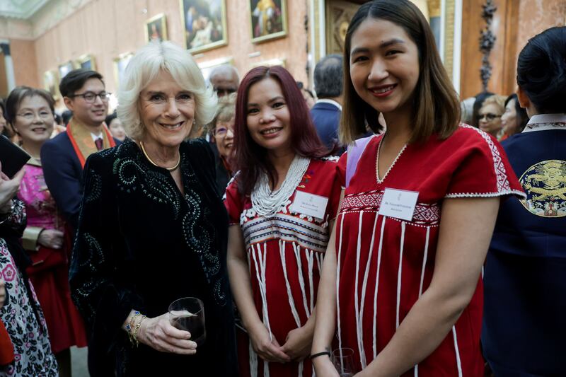 Queen Consort Camilla poses with two guests at the reception. PA