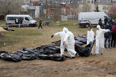 Men in protective gear carry the body of a civilian killed in Bucha, Ukraine, in April 2022. AP