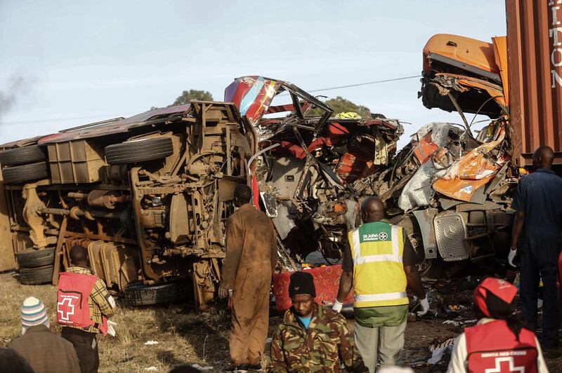 Emergency workers stand near the wreckage of a bus and a lorry that crashed in a head-on collision, killing thirty people, at the accident scene near Nakuru, Kenya, on December 31, 2017.
Thirty people were killed and 16 injured early on the morning of December 31 in a head-on collision between a bus and a lorry on a road in central Kenya, police said. The accident occurred close to a notorious stretch on the Nakuru-Eldoret highway when a bus travelling from Busia, in western Kenya, collided with a truck coming from Nakuru. Police said the death toll for that stretch of road has now reached 100 this month alone. / AFP PHOTO / STR