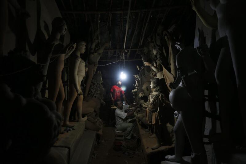 Ramesh Chitrakar, seated, works on idols of Hindu goddess Durga, in New Delhi.  Saurabh Das / AP Photo