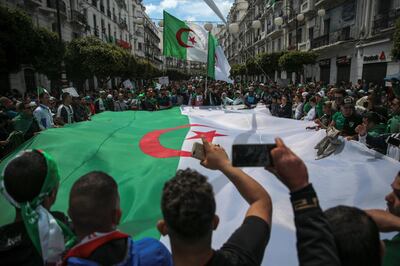 Protestors carry a large flag and chant slogans during a demonstration against the country's leadership, in Algiers, Friday, April 12, 2019. Heavy police deployment and repeated volleys of water cannon and tear gas didn't deter masses of Algerians from packing the streets of the capital Friday, insisting that their revolution isn't over just because the president stepped down. (AP Photo/Mosa'ab Elshamy)