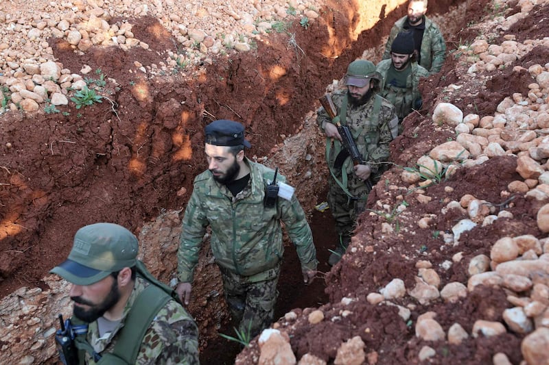 Syrian rebel fighters for the National Liberation Front walk along a trench on the front line of a battle with regime forces in Idlib province. The conflict in Syria has been going on for 10 years. AFP