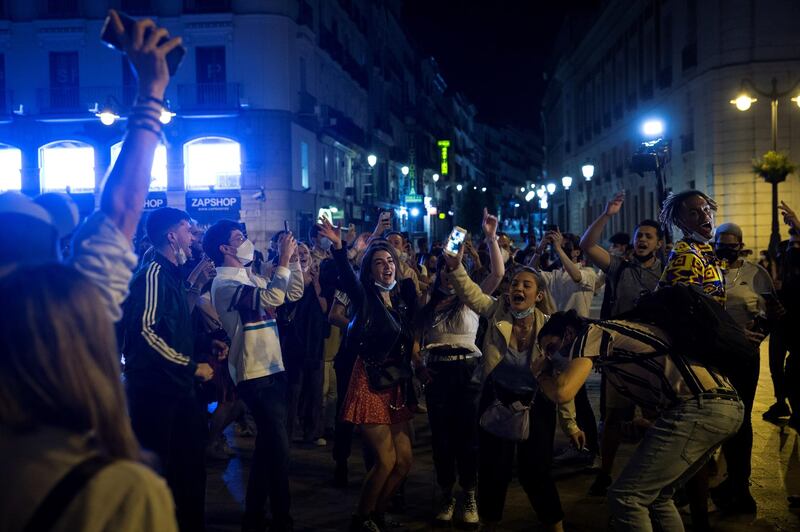 Hundreds of young people celebrate the end of a nationwide curfew put in place to prevent the spread of the coronavirus at Madrid's Puerta del Sol square late on Saturday.  EPA