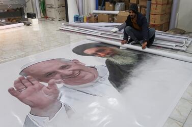 A worker rolls a poster of Pope Francis and Iraq's top Shi'ite cleric, Ayatollah Ali al-Sistani, ahead of the Pope's planned visit to Iraq, at a shop in Najaf, Iraq, February 28, 2021. Reuters/Alaa Al-Marjani