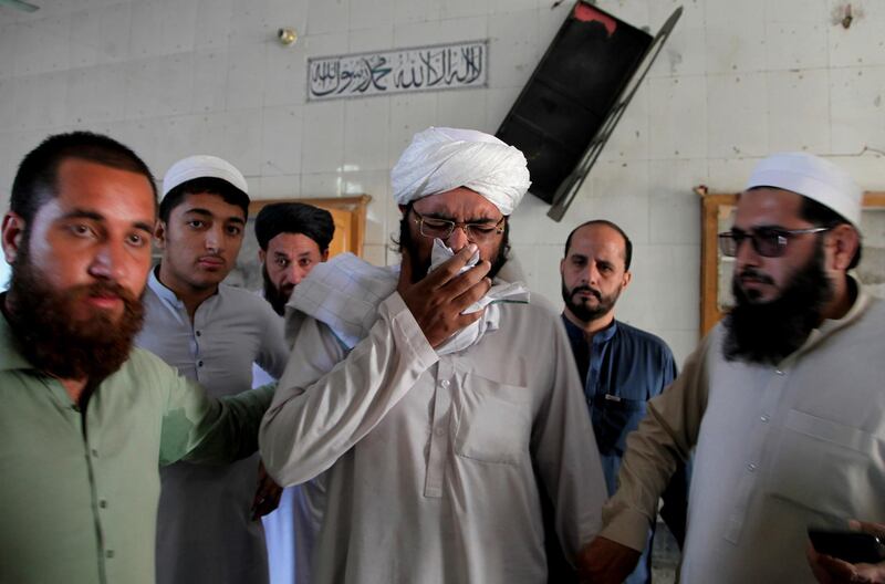 People comfort a cleric who mourns over lost of his students at the site of a bomb explosion in an Islamic seminary, in Peshawar, Pakistan. AP Photo