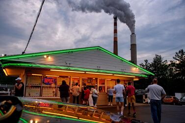 People line up for ice cream at Glens Custard in the shadow of GenOns Cheswick Power Station in Pennsylvania which still burns coal to produce 637MW of electricity for the region. Spending on renewables fell 8% last year, according to the IEA, which expects a rebound in 2021. Getty Images/AFP