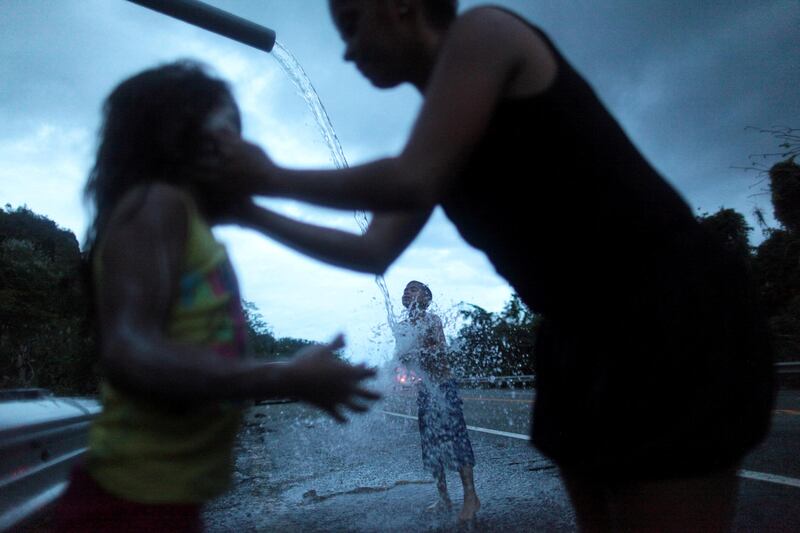 A family bathe with mountain spring water after hurricane Maria hit the area in September, in Utuado, Puerto Rico. Alvin Baez / Reuters