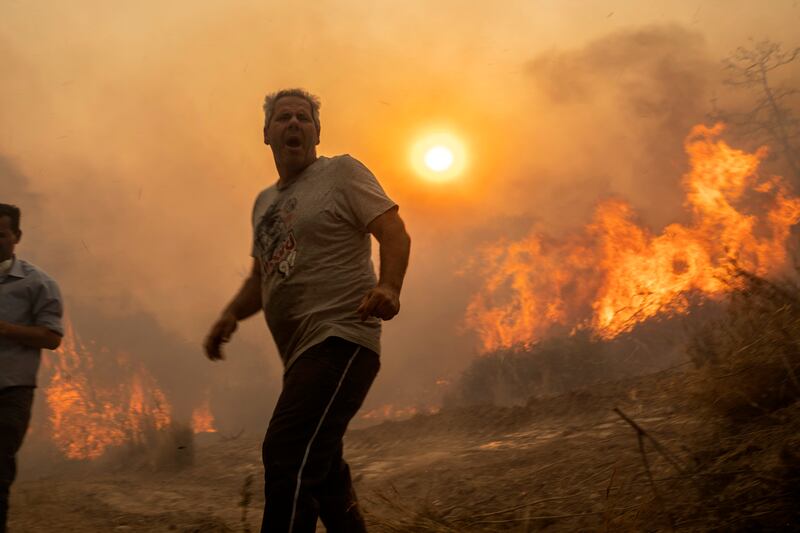 Residents of Gennadi village stand near a forest fire raging on the island of Rhodes. AP