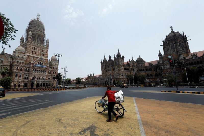 A man walks with his bicycle in front of the Brihanmumbai Municipal Corporation (BMC) building and the Chhatrapati Shivaji Maharaj Terminus (CSMT) during a weekend lockdown to limit the spread of the coronavirus disease (COVID-19) in Mumbai, India, April 10, 2021. REUTERS/Francis Mascarenhas