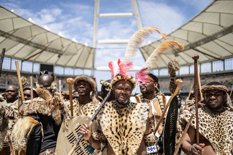 Amabutho, Zulu King regiments, clad in traditional dresses and carrying shields and sticks, are seen at the Moses Mabhida Stadium in Durban on October 29, 2022, for the handover of the official certificate of recognition for the Zulu King Misuzulu.  - Tens of thousands of people in colourful regalia gathered at a huge soccer stadium in the coastal city of Durban to celebrate the official coronation of South Africa's Zulu king.  Misuzulu Zulu, 48, ascended the throne once held by his late father, Goodwill Zwelithini, who died in March 2021 after a diabetes-related illness.  (Photo by Marco LONGARI  /  AFP)