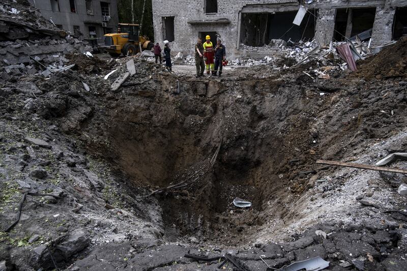 State workers and Ukrainian military personnel inspect the crater left behind by a missile strike in Dnipro, in May 2023. Getty Images