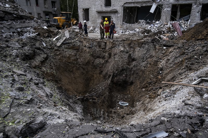 State workers and Ukrainian military personnel inspect the crater left behind by a missile strike in Dnipro, in May 2023. Getty Images