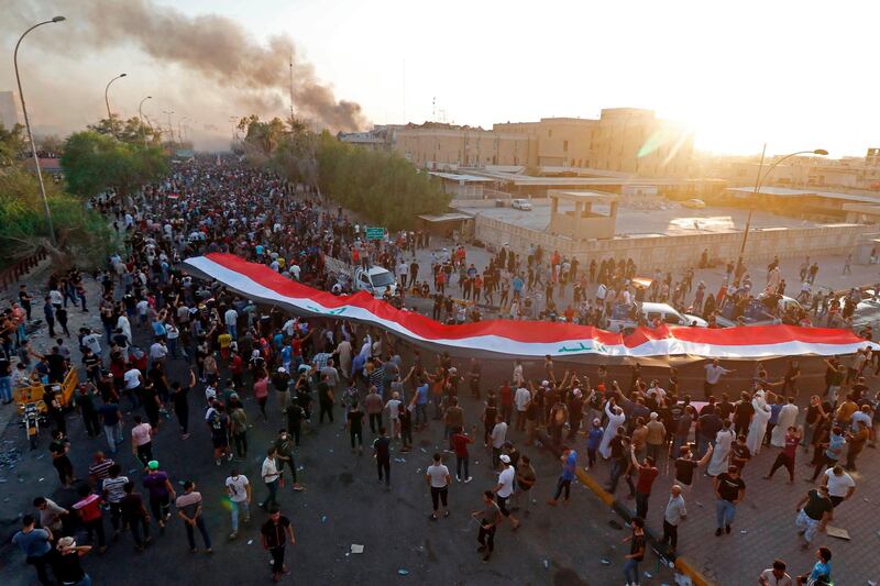 Iraqi protesters wave their national flag in front of official buildings. AFP