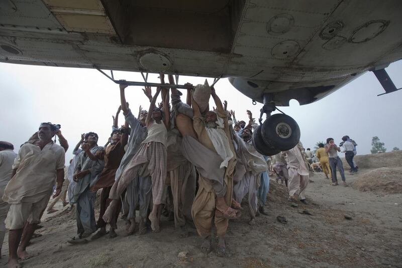 Flood victims try to grab onto the side bars of a hovering army helicopter which arrived to distribute food supplies in the Muzaffargarh district of Pakistan’s Punjab province on August 7, 2010. Adrees Latif / Reuters