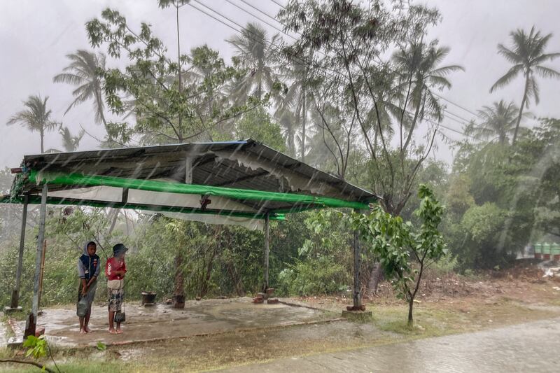 Two children seek shelter as rains caused by approaching Cyclone Mocha fall in Sittwe, in Myanmar's Rakhine State. AP