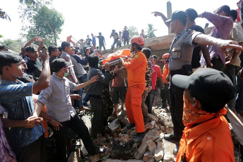 Rescue workers and police remove a victim from a collapsed building following an earthquake in Lueng Putu. Antara Foto / Irwansyah Putra / via Reuters
