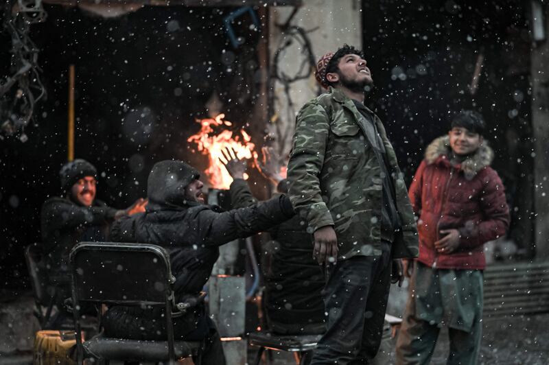 People gather around a fire as the first snowflakes fall.