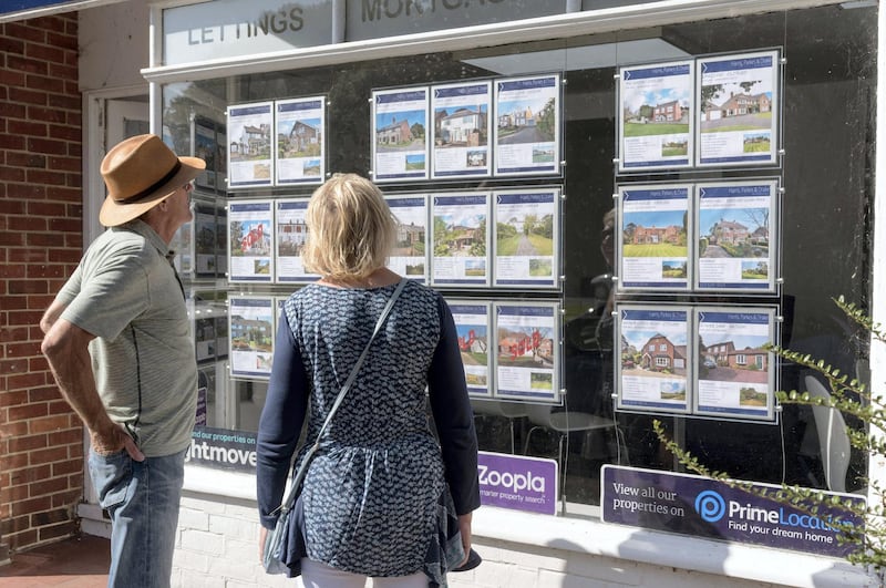 Couple looking in an estate agent's window at properties for sale. England UK. (Photo by: Education Images/Universal Images Group via Getty Images)