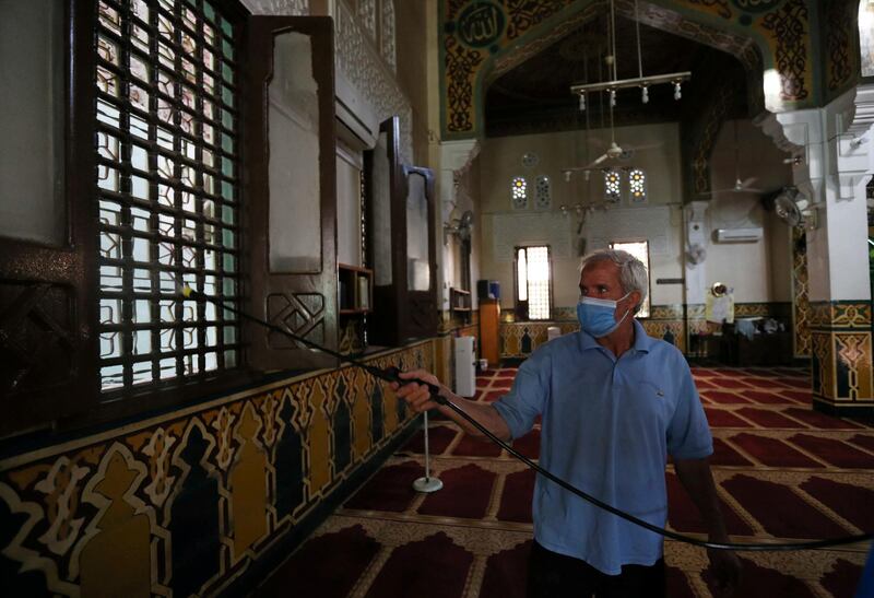 A volunteer wearing a face mask sprays disinfectant inside a mosque in Cairo.  Reuters