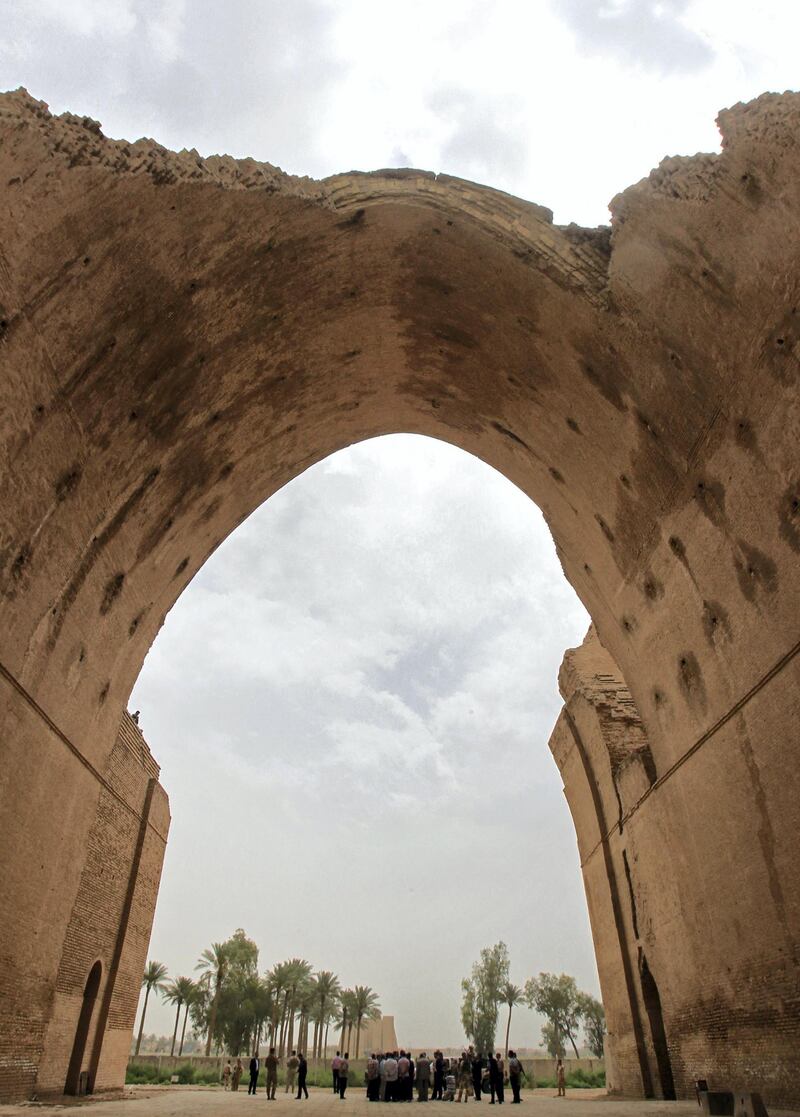 Iraqis stand under the arch of the barrel-vaulted hall of the Ctesiphon palace, which was in the imperial capital of the Persian Empire in the Parthian and Sassanian times, near Madean, 30 kilometres south of Baghdad, on May 15, 2013. A foreign company is planning a project to stabilize the arch which has a span of more than 80 feet, and reaches a height of 118 feet, after parts of it began to crumble.  AFP PHOTO / ALI AL-SAADI (Photo by ALI AL-SAADI / AFP)