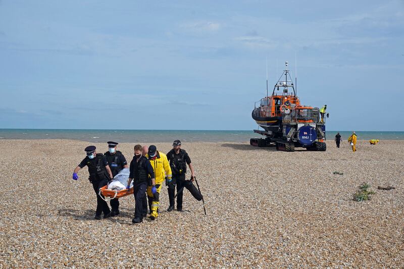 Police officers and members of the RNLI carry a person from a boat on the Dungeness coast. AP