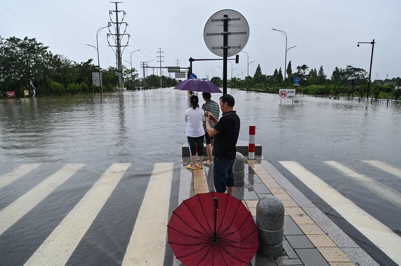 People look out at a flooded road in Yuyao.
