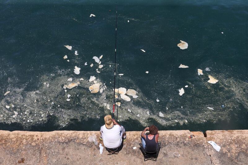 A fisherman dangles his line to catch fish in polluted water off Beirut's seaside Corniche, Lebanon.  Reuters