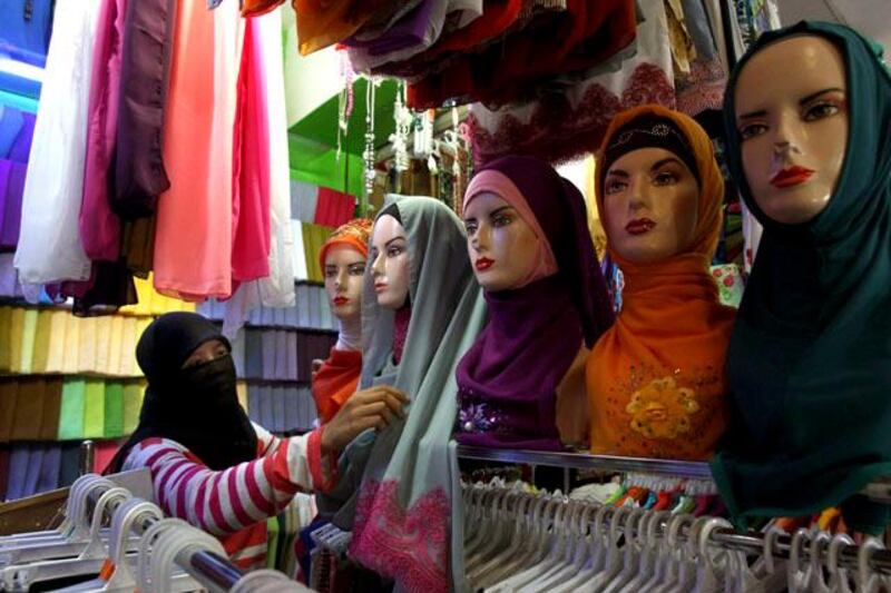 A shopkeeper arranges the display at a shop that sells Muslim headscarfs at a shopping mall in Jakarta, Indonesia, Monday, July 8, 2013. Muslims around the world will start observing the holy fasting month of Ramadan this week. (AP Photo/Tatan Syuflana)