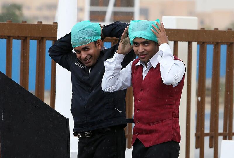 Workers cover their heads with plastic bags at Dubai Investment Park. Pawan Singh / The National