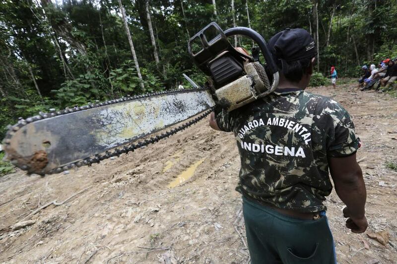 A Ka’apor Indian warrior carries a confiscated chainsaw. The words on the warrior’s shirt read, ‘Indigenous Environmental Guard’.