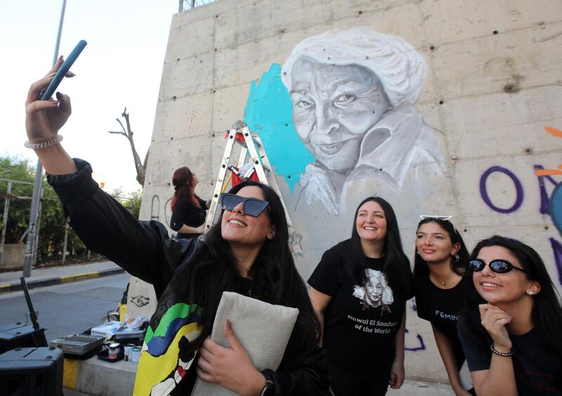 Lebanese women take a selfie as Ms Abdo makes the finishing touches to her portrait of Nawal El Saadawi. AFP