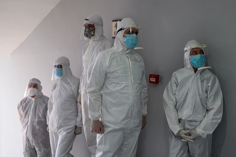 Health officer wearing protective clothing speak as they prepare before travelling to collect swab samples from confined people who are believed to have been in contact with coronavirus patients. AFP