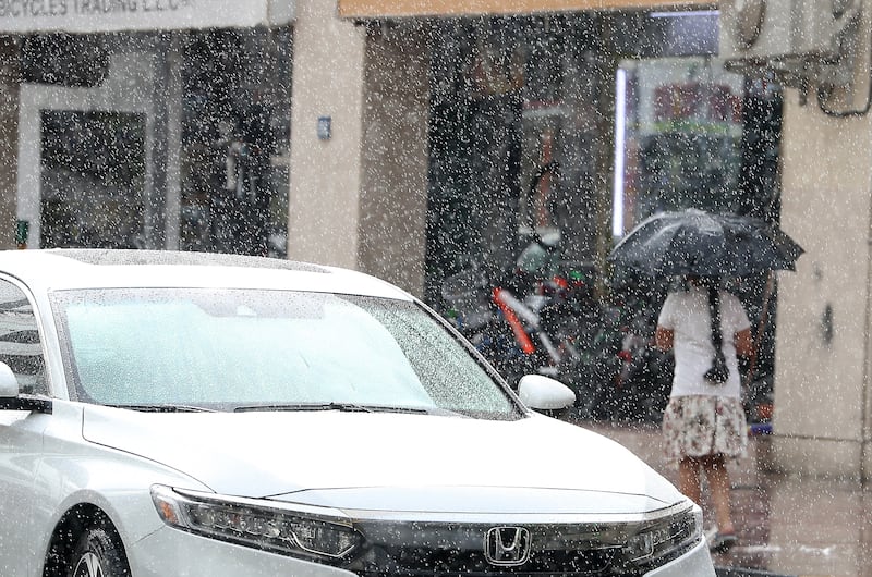 A girl holding umbrella to shelter from a downpour in the Al Karama area of Dubai. Pawan Singh / The National