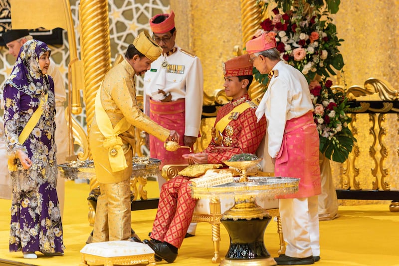 Brunei's Sultan Hassanal Bolkiah pours scented oil on the hands of Prince Abdul Mateen during the royal powdering ceremony at Istana Nurul Iman, ahead of his wedding to Anisha Rosnah, on January 10, 2024. AFP
