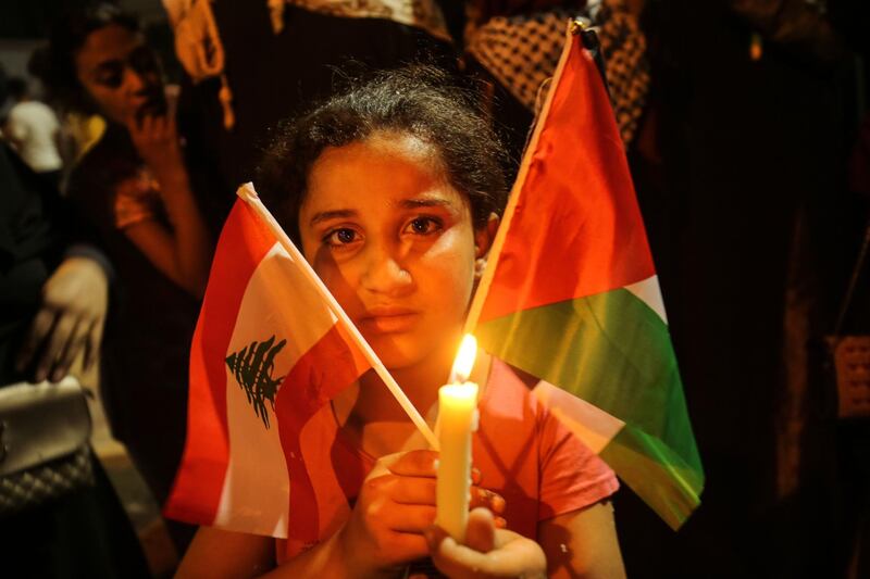 A Palestinian girl carries the national flag and the Lebanese flag during a candlelight vigil in Rafah in the southern Gaza Strip, in support of Lebanon a day after a blast in a warehouse in the port of the Lebanese capital sowed devastation across entire city neighbourhoods. AFP