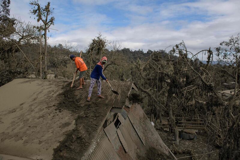 People clear ash from their roof in the village of Buso-Buso. AFP